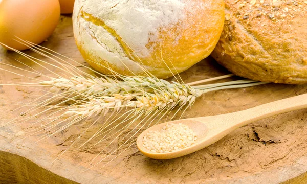 Pane fresco e grano sul legno — Foto Stock