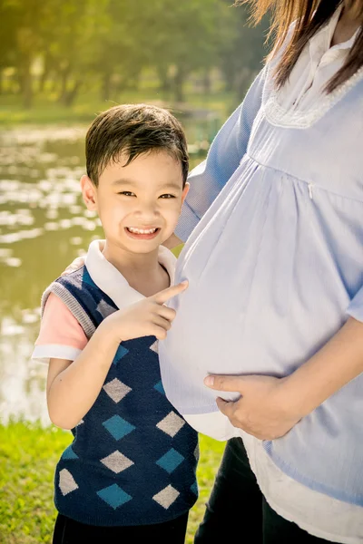 Asian boy kissing the belly of his pregnant mother — Stock Photo, Image