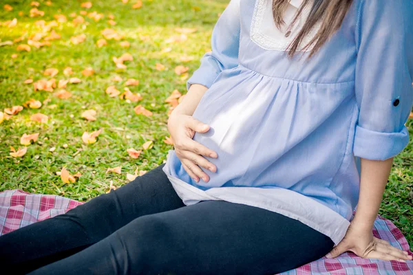 Young pregnant woman relaxing in park outdoors, — Stock Photo, Image