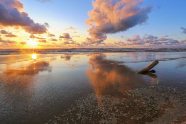 Fırtınalı yaz gününde, renkli günbatımında küçük bir kasaba olan Saulkrasti 'de beyaz kumlu sahil. 