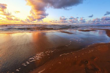 Fırtınalı yaz günbatımında küçük bir kasaba olan Saulkrasti 'de beyaz kumlu plaj. 