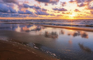 Küçük bir kasaba olan Saulkrasti 'de, fırtınalı yaz günbatımında beyaz kumlu sahil. 