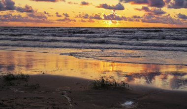 Fırtınalı yaz günbatımında küçük bir kasaba olan Saulkrasti 'de beyaz kumlu plaj. 