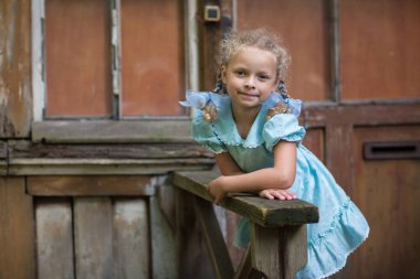 Evinin verandasında duran mavi saçlı, at kuyruklu bir kız. Sovyetler Birliği 'nden çocuklar