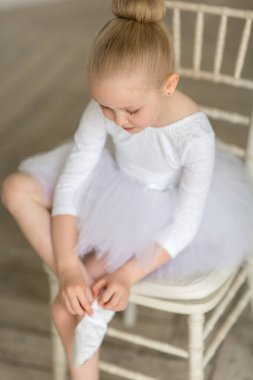 Beyaz etekli küçük şirin balerin bir nokta takıyor.