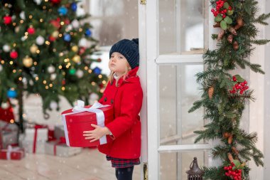 İlyuminatsii Noel ağacının orada kırmızı ceketli tatminsiz bir kız elinde hediye kutusuyla dikiliyordu.