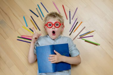 Kırmızı tişörtlü, gözlüklü, kafası karışık sarışın çocuk yerde kalemin yanında yatıyordu. Şaşırma hissi, fikir.