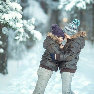 İki kardeş karlı bir ormanda ağacın altında saklanıyor..