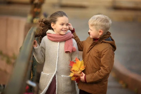 男の子と可愛い女の子のロマンチックな散歩は 秋のメイプルの花束を持っています 街を歩く — ストック写真