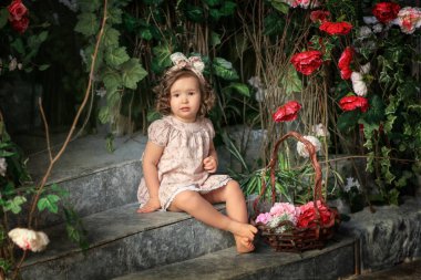 Taş basamaklarda oturan kız pembe bir elbiseyle elinde bukleli bir sepet gülle.