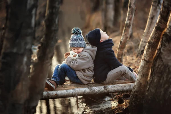 コートを着た二人の男の子が公園に座っている 子供たちはおもちゃで春に歩く — ストック写真