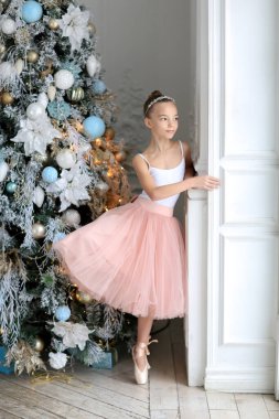 Noel ağacının yanında balerin etekli ve sivri uçlu ayakkabılı bir kız. Yeni Yıl ve Noel