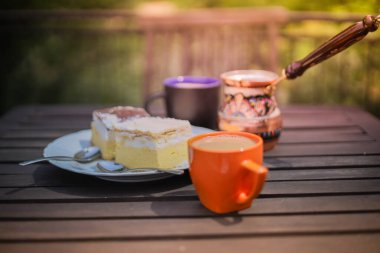 Kırsal kahvaltı. Kahve fincanlı ahşap kahve masası, Céve gölü kremalı pasta, lezzetli Slovenian tatlıları. Kremna Rezina veya Cremeschnitte