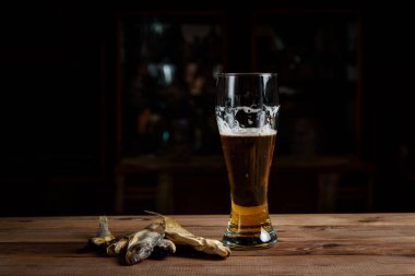 Tahta bir masada bir bardak bira ve kurutulmuş balık.