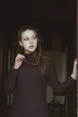 Güzel bir kız elinde bardak tutar ve bir şeyler düşünür..