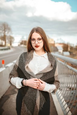 Sokakta omuzlarında ekose atkıyla gözlüklü bir kız..