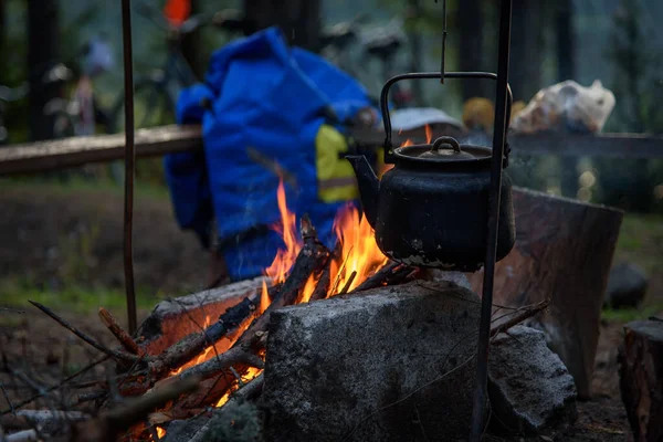 The kettle stands over a fire in the forest. A smoked kettle over the fire. — Stock Photo, Image