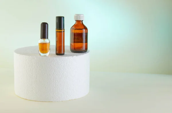 Dropper Bottle - Amber Glass of perfume, shower gel, unlabeled bottles on white podium.