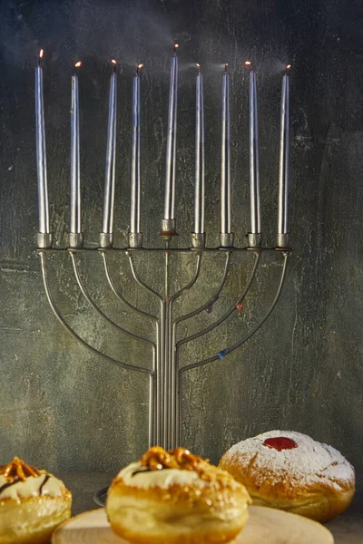 Jewish holiday Hanukkah background with menorah - traditional candelabra with candles and donuts