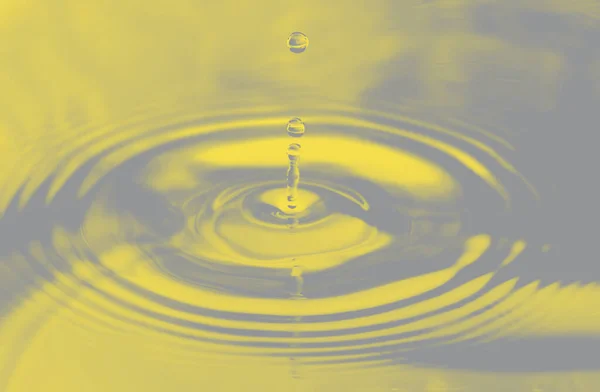 Yellow background, texture. Drops falling in water and circles walking on water, with reflection