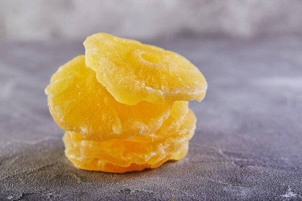 Желтые консервированные ананасовые кольца на сером бетонном фоне. Сушеные фрукты, тренд цвета 2021. Копирование текста.