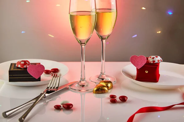 バレンタインデーやキャンディーハートのロマンチックな誕生日ディナー シャンパンのグラス 背景に反射と照明を備えたエレガントなテーブルセッティング — ストック写真