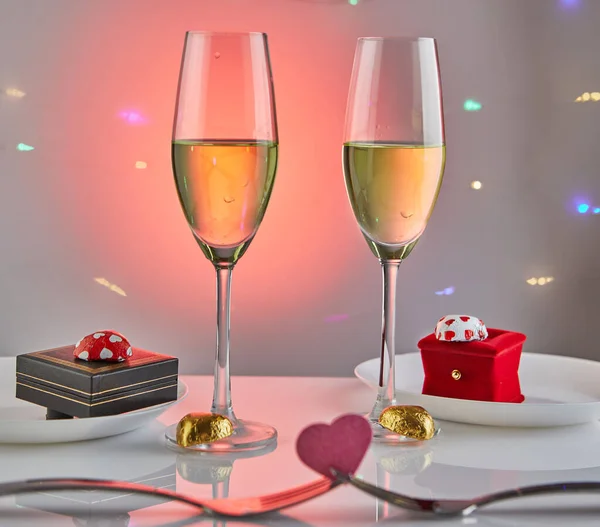 Sevgililer Günü ya da romantik bir doğum günü yemeği içinde şeker kalpler, şampanya bardakları ve arka planda yansıma ve ışık olan zarif bir masa. — Stok fotoğraf