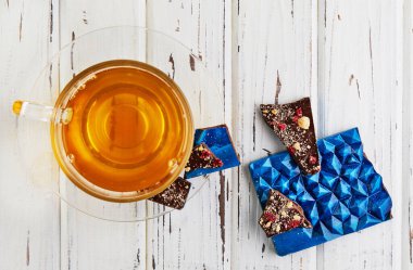 Ametist şeklinde çikolata ve beyaz ahşap arka planda bir fincan çay. Tatil için bir hediye..