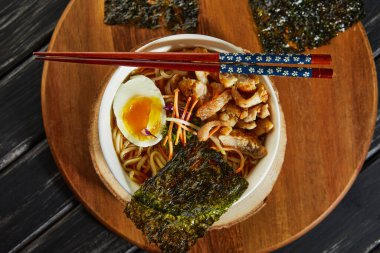 Japon eriştesi çorbası, tavuk, yumurta, sarımsak ve erişteli ve ahşap kaplama. Asyalı Miso Ramen eriştesi. Düz yatıyordu
