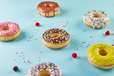 Mavi arka planda kremalı ve şekerli çok renkli çörekler..