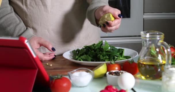 Donna cucina secondo il tutorial di classe master virtuale online, E guardando sulla ricetta digitale, utilizzando tablet touchscreen durante la cottura pasto sano in cucina a casa — Video Stock