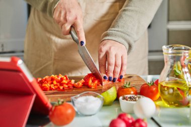 Online sanal uzmanlık kursuna göre yemek pişiren bir kadın ve dijital tarife bakıp evde mutfakta sağlıklı yemek pişirirken dokunmatik ekran tableti kullanan bir kadın..