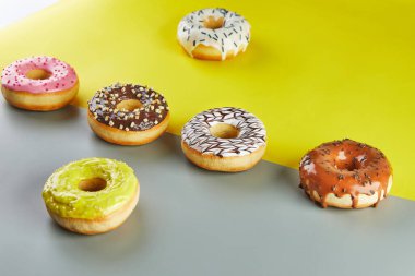Çok renkli donutlar ve sarı-gri arka plan üzerine serpiştirilmiş jöleler..