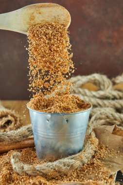 Teff, eski glütensiz tahıllara bir alternatif. Tahta kaşıktan kovaya Teff damlıyor..