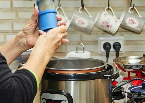 Fleisch in einem langsamen Herd kochen, eine Frau pfeffert das Fleisch. — Stockfoto