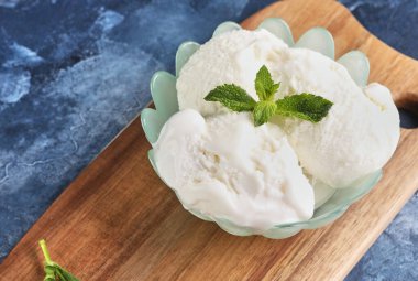 Vazoda kremalı dondurma ve mavi arka planda nane yaprağı..