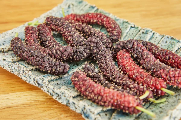 Afghan mulberry black and red lying on plate, close-up.