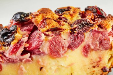 Bitmiş vişneli turta dilimi, çatallı gri tabakta clafoutis. Kapat.