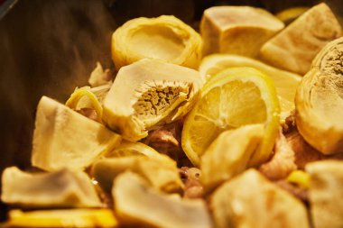 Limonlu kuzu, enginar ve kişniş sapları kazanda düşük ısıda kızartılır..