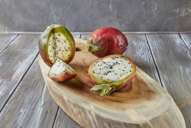 Peru elmalı kaktüs meyvesi bütün ve gri tahtada ahşap tezgahta kesilmiş. Bilimsel adı Cereus repandus.