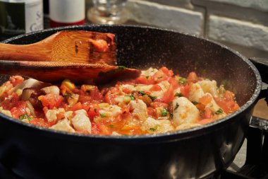 Rezene domatesli ve fesleğenli levrek balığı gaz sobasında tavada kızartılır..