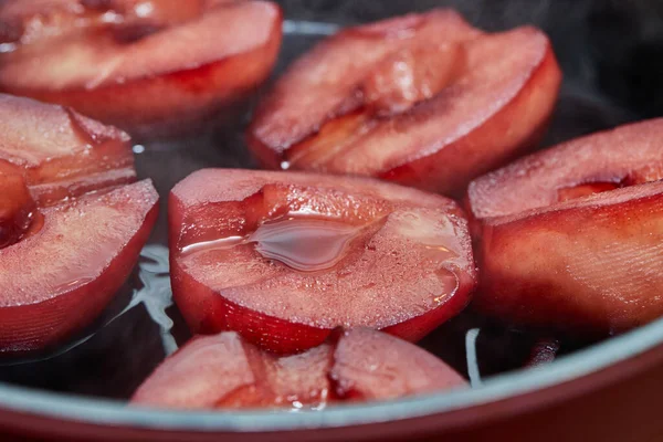 Cut pears are boiled in red syrup with wine on gas stove