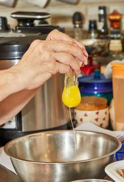 Cozinheiro adiciona um ovo à tigela de ingredientes para preparar o prato — Fotografia de Stock