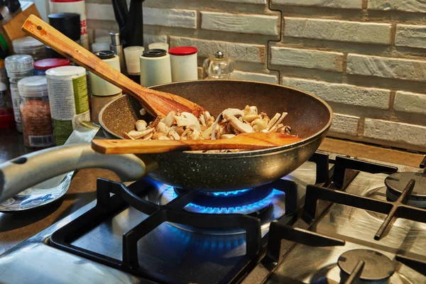 Porcini e champinhons são fritos em frigideira em fogo alto no fogão a gás — Fotografia de Stock