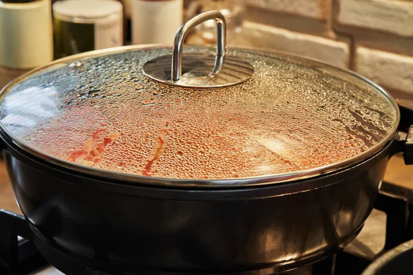 Капли на стеклянную крышку сковороды готовят блюдо на духовке с избирательным фокусом — стоковое фото