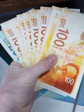 Bir el İsrail 'in yeni şekel banknotlarını tutuyor, canlı para birimi tasarımı ve finansal ayrıntıları sergiliyor..