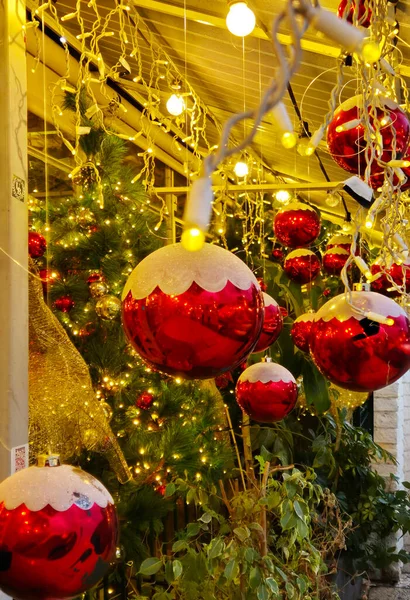 Kırmızı Noel süslerinin ve süslenmiş bir ağacın üzerinde parlayan sarı ışıkların yakın görüntüsü sıcak ve şenlikli bir tatil atmosferi yaratıyor..