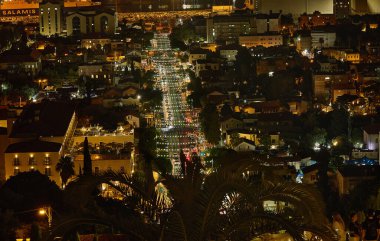 Hayfa, İsrail - 9 Ekim 2025: Trafik ışıklarıyla aydınlatılmış, palmiye ağaçları ve binalarla çerçevelenmiş, limana doğru giden Hayfa caddesinin görüntüsü.