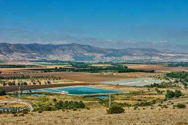 Sulama göletleri ve ekili tarlalar uzak tepelerin altına uzanır parlak mavi gökyüzünün altında kırsal bir tarım arazisinde.