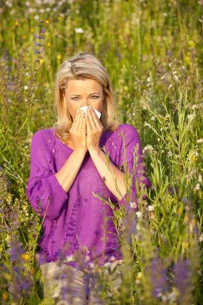 Привлекательная женщина на цветочном поле с аллергическими симптомами — стоковое фото